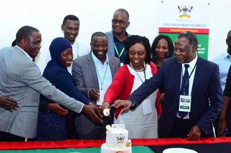 Professor Damalie Nakanjako (2nd right), Dr. Besigye Innocent (3rd right) and Dr. Fred Bukachi (1st right) cutting cake with other key stakeholders at the symposium
